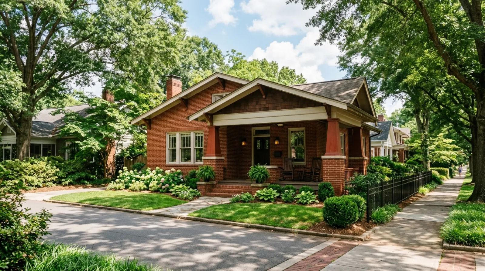 A red brick craftsman bungalow with a deep front porch on a tree-lined Charlotte street